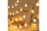 String lights with star-shaped bulbs on a table with a mug and books in the background.