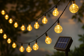 String of decorative lights with a solar panel power source, glowing in the dark.