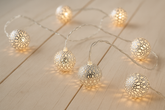 String of decorative lights with spherical bulbs on a wooden surface