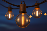 String of illuminated light bulbs against a dark blue sky
