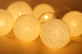 String of white cotton ball lights with a warm glow on a blurred background