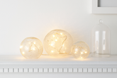 Three glass bulb lights on a white surface with a white frame in the background