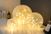 Three glowing spherical lights on a surface with a phone and picture frame in the background.