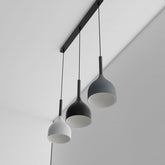 Three pendant lights hanging from a ceiling fixture against a plain background