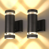 Two black cylindrical wall lights on a wall with warm glow.