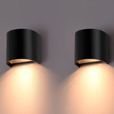 Two black wall lights emitting a warm glow on a gray background