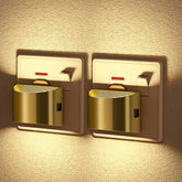 Two gold light switches on a textured wall with warm lighting.