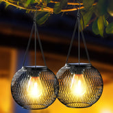 Two hanging solar lights with glowing bulbs against a blurred natural background