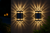 Two outdoor wall lights casting geometric shadows on a wall at night.