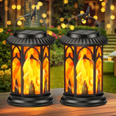 Two solar-powered lanterns with flame design on a wooden surface outdoors.
