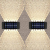 Two solar-powered wall lights on a textured wall.
