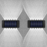 Two solar panels mounted on a textured white wall.