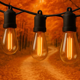 Three illuminated light bulbs on a string against an orange background