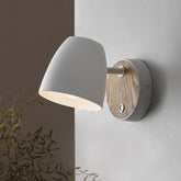 Wall-mounted light fixture with a wooden accent on a neutral wall.