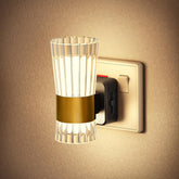 Wall-mounted light fixture with glass shade and gold accent on a beige wall.
