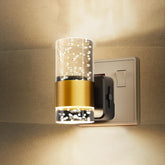 Wall-mounted light fixture with gold and clear design on a beige wall.