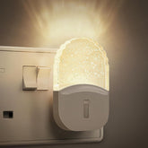 Wall-mounted night light emitting a warm glow on a neutral background