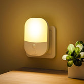 Wall-mounted night light emitting a warm glow on a wall with a plant in the corner.