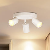 White ceiling light fixture with three adjustable lights on a beige ceiling.
