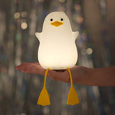 White duck-shaped night light held in a hand with a blurred background