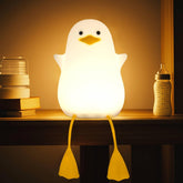 White duck-shaped night light on a shelf with books and a bottle in the background