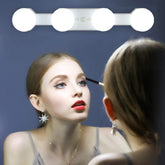 Woman applying makeup in front of a mirror with LED lights.