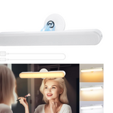 Woman applying makeup in front of a mirror with a light bar above it