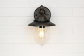 Black wall-mounted light fixture on a white tiled wall