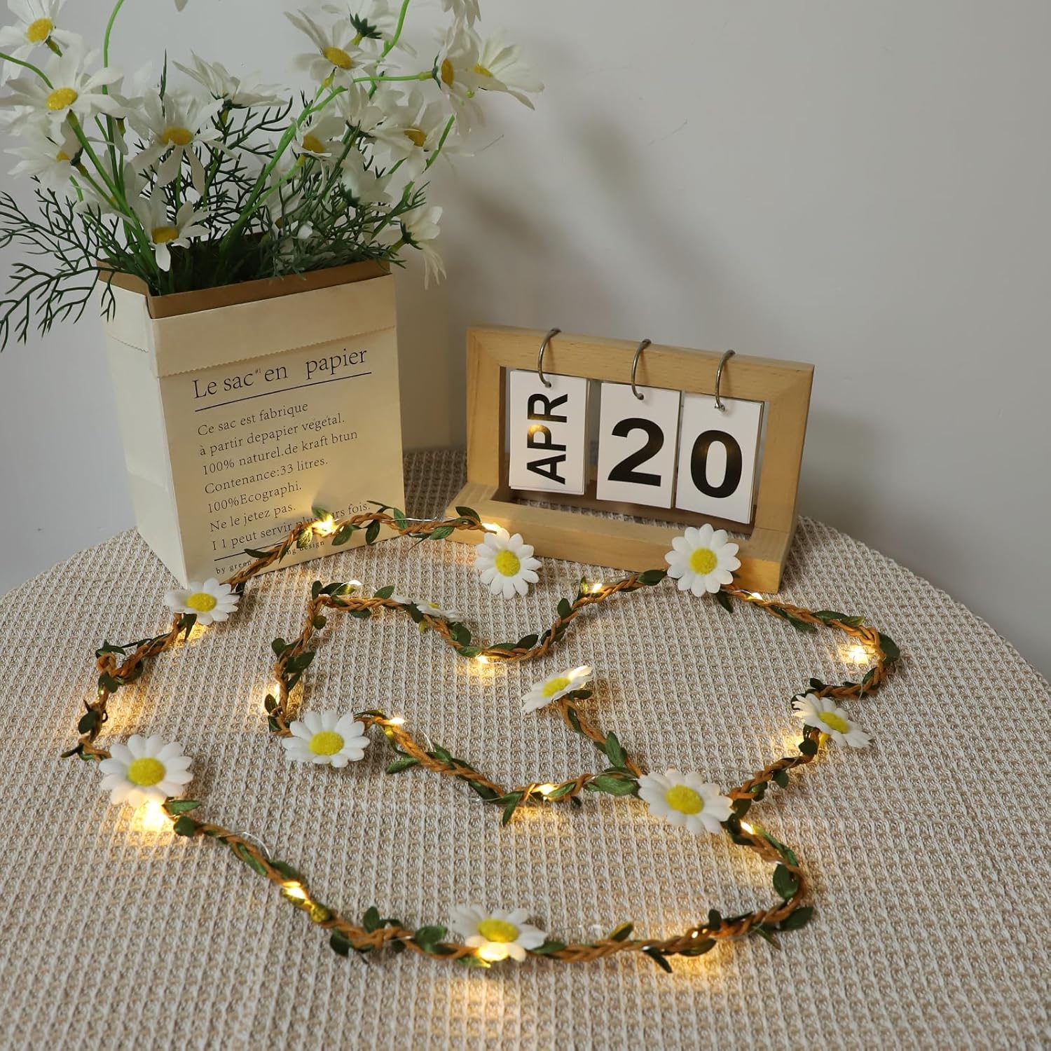 Decorative string lights with flowers and a small calendar on a textured surface.