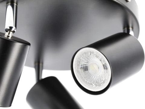 Close-up of a modern ceiling light fixture with three black cylindrical lights.