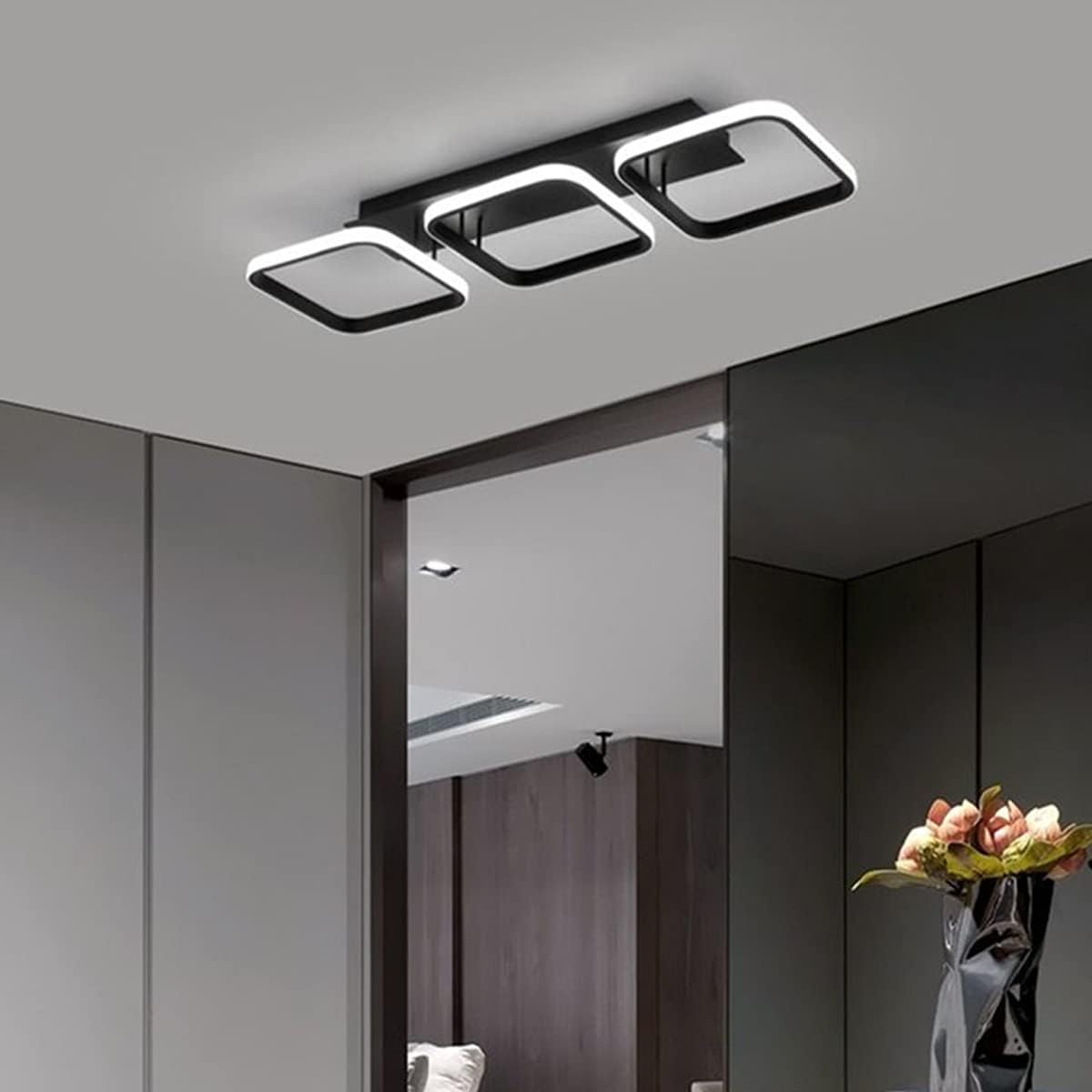 Modern ceiling light fixture in a room with a vase of flowers on a table.