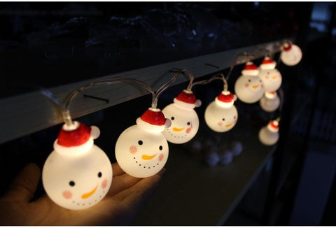 String lights shaped like snowmen with red hats on a dark background