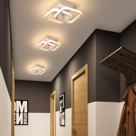 Modern ceiling lights in a hallway with dark walls and a coat hanging on the right.