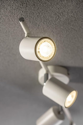 White ceiling light fixture with three adjustable arms on a gray ceiling.