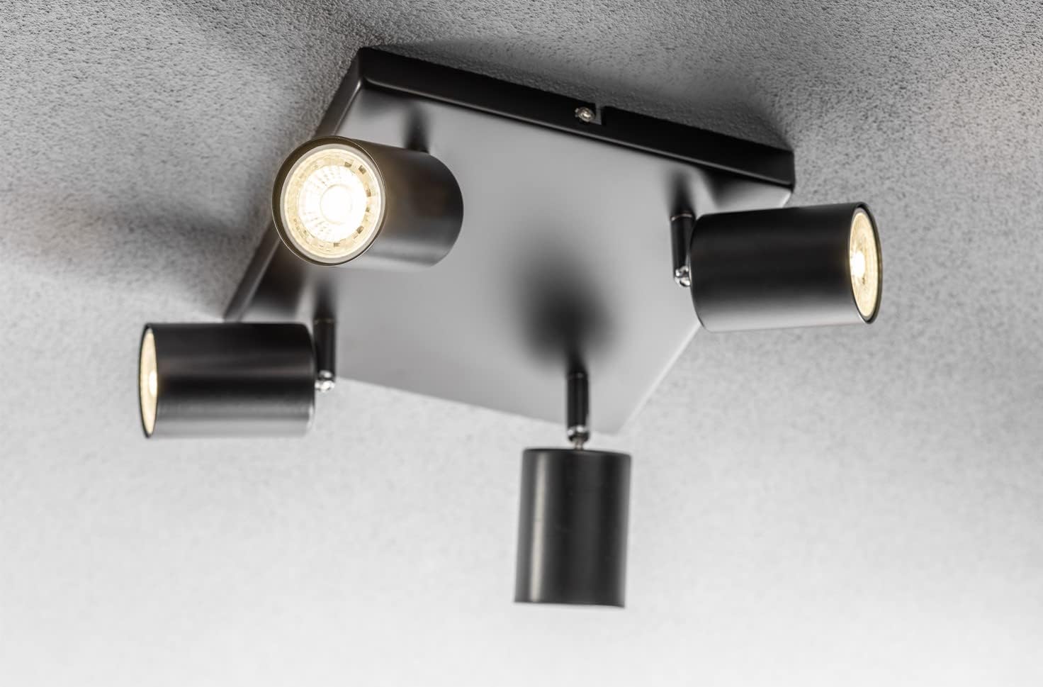 Modern ceiling light fixture with four cylindrical lights on a gray background