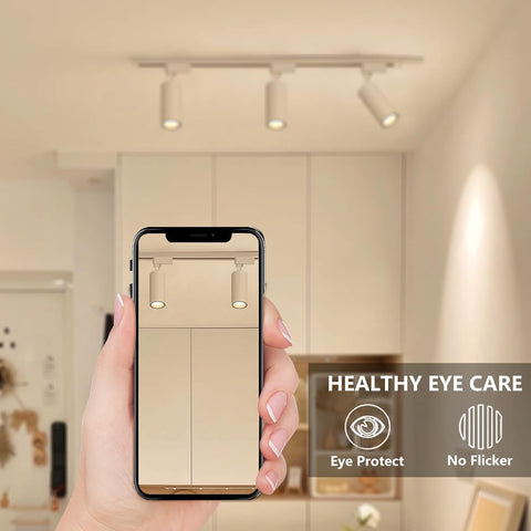 Hand holding a smartphone displaying a light fixture app with 'Healthy Eye Care' features on a blurred kitchen background.