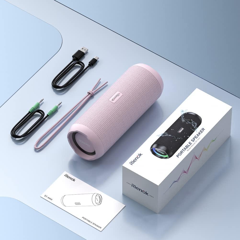 Pink portable speaker with accessories and packaging on a light blue surface