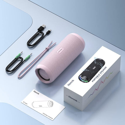 Pink portable speaker with accessories and packaging on a light blue surface