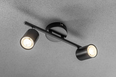 Black ceiling light fixture with two illuminated bulbs on a gray background