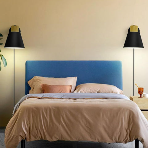 Bedroom with a blue headboard, beige bedding, and two black floor lamps.
