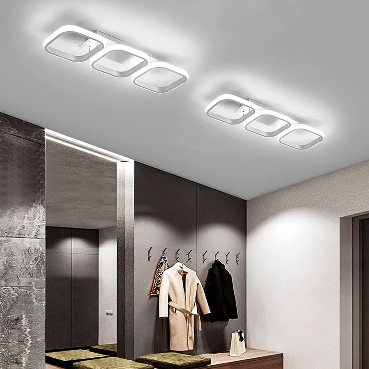 Modern ceiling lights in a hallway with coats hanging on hooks.