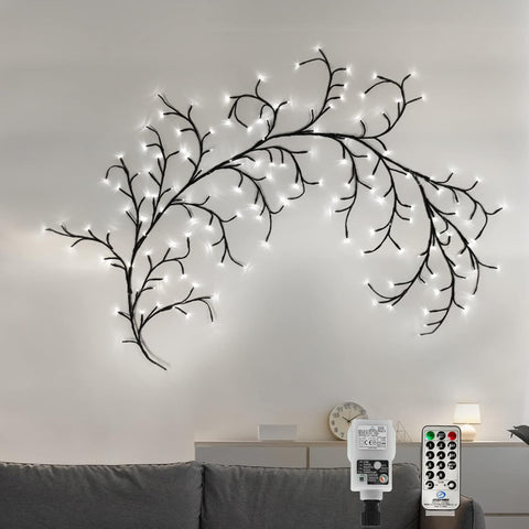 Decorative wall light fixture shaped like branches with lights on a plain wall.