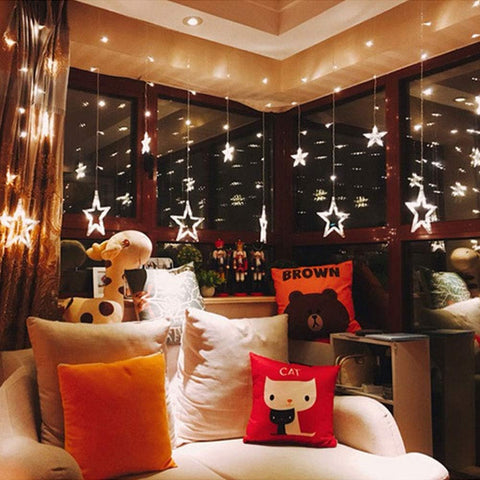 Decorative indoor setting with star-shaped lights, pillows, and a teddy bear.
