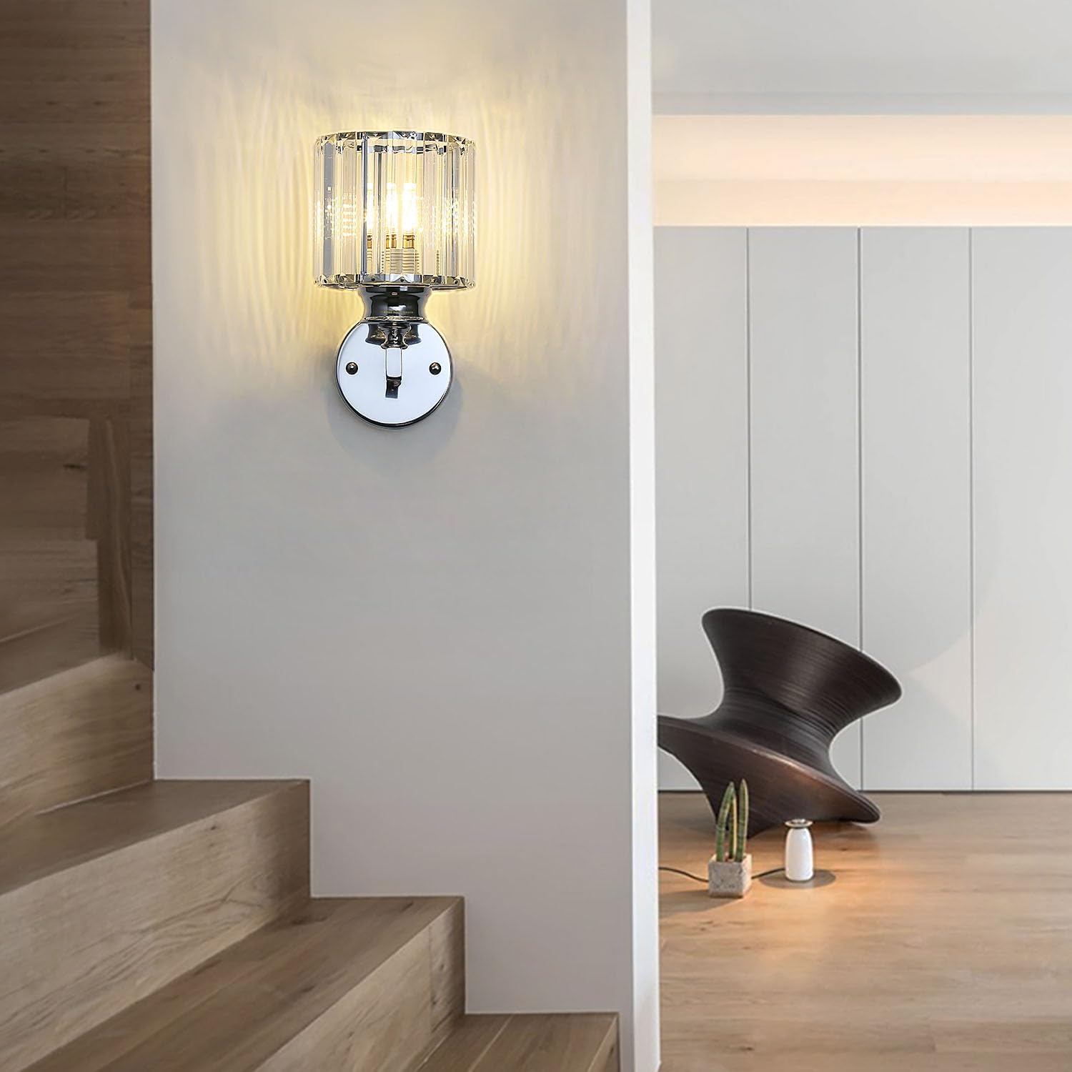 Modern wall light fixture on a wall next to a staircase with a chair and decor items in the background.
