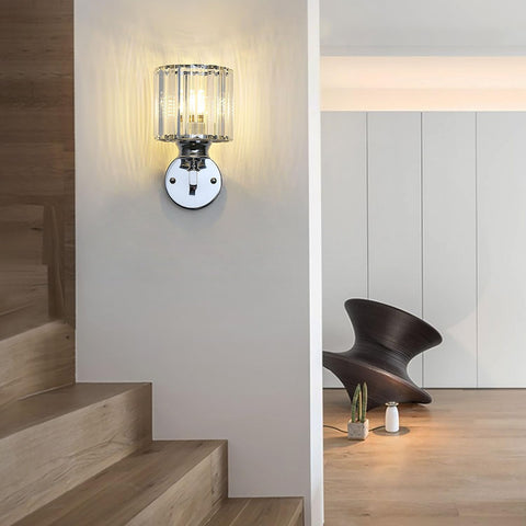 Modern wall light fixture on a wall next to a staircase with a chair and decor items in the background.