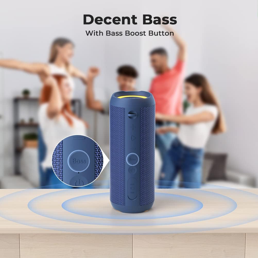 Blue portable speaker with bass boost button on a wooden surface, people dancing in the background.