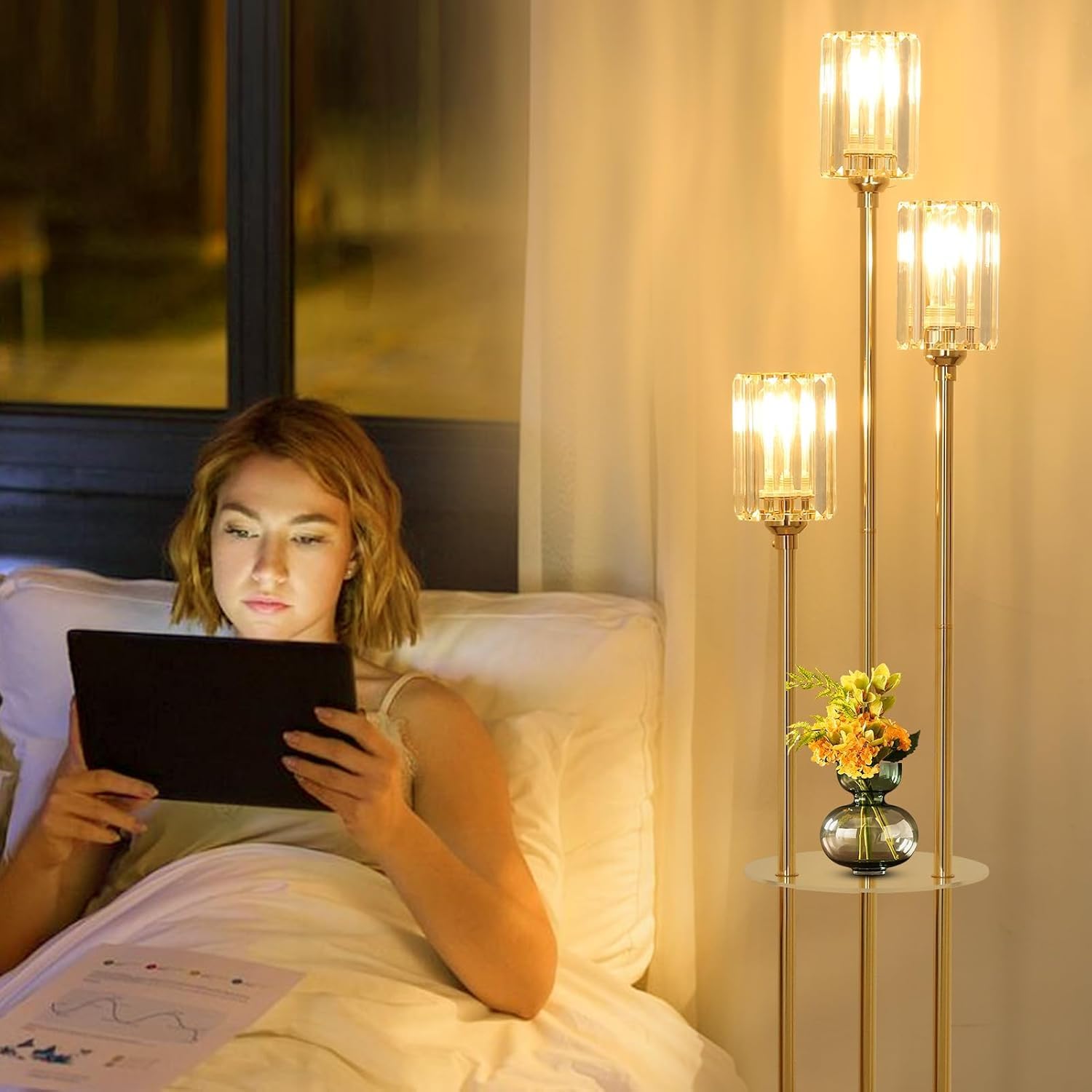 Woman lying in bed using a tablet in a softly lit bedroom.
