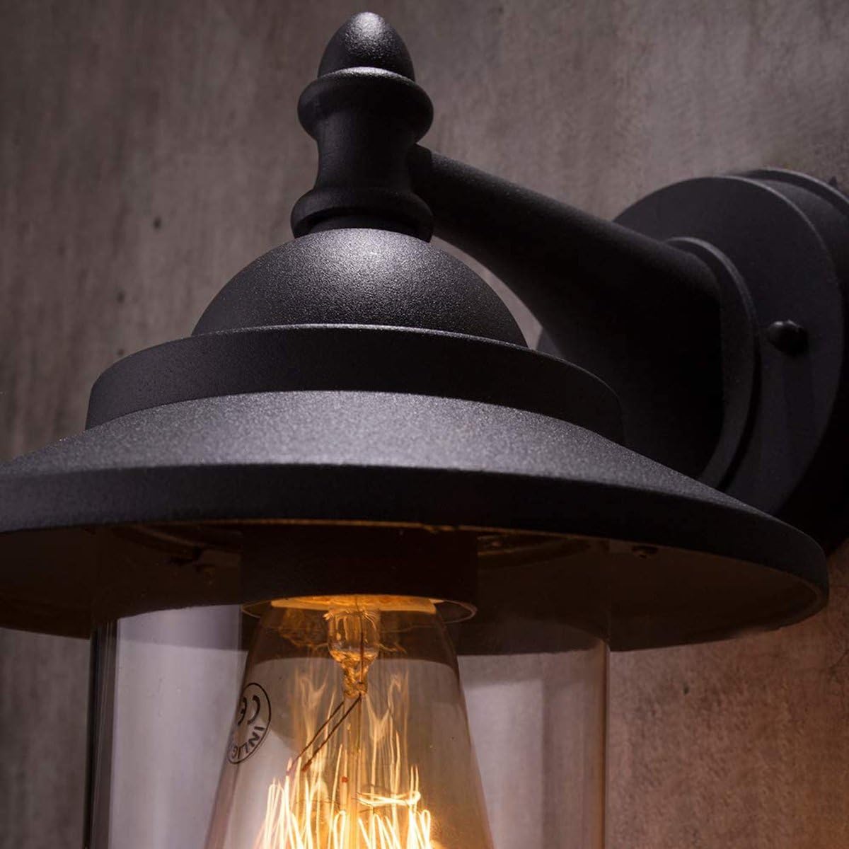 Black outdoor wall light fixture with a lit bulb against a neutral background