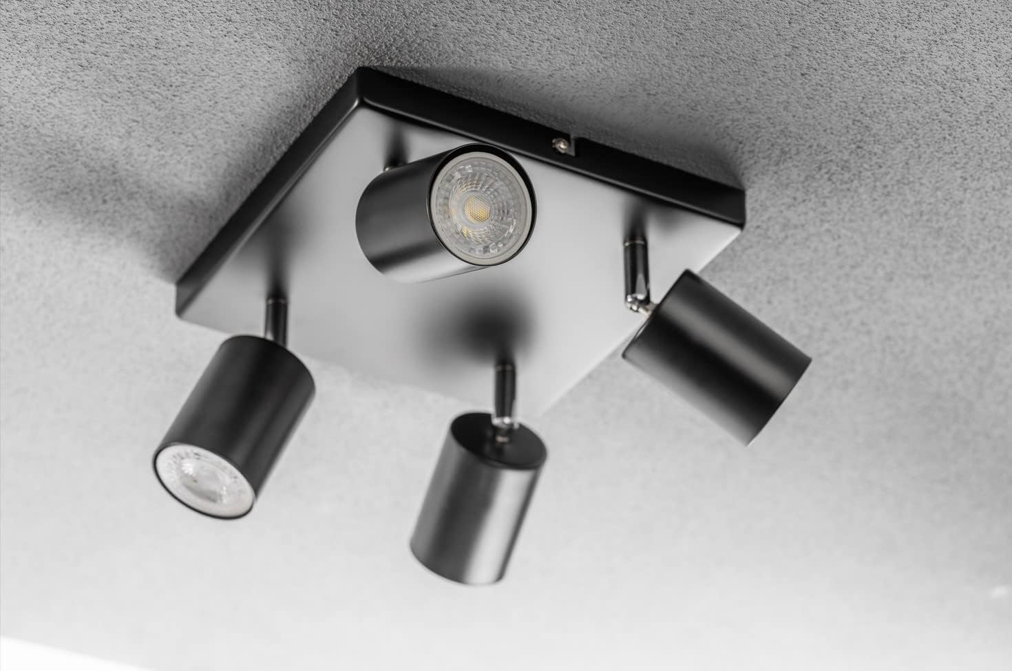 Modern ceiling light fixture with four cylindrical lights on a gray background