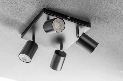 Modern ceiling light fixture with four cylindrical lights on a gray background